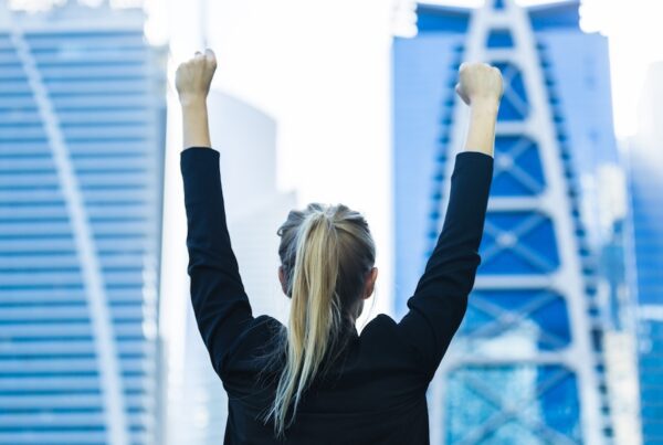 Business success - Celebrating businesswoman overlooking the city center high-rises.