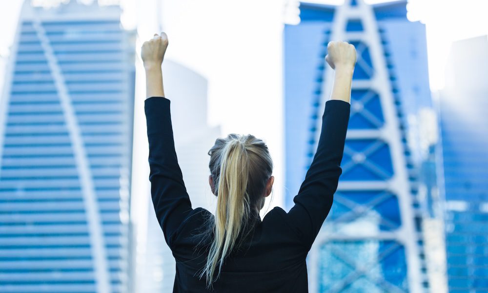 Business success - Celebrating businesswoman overlooking the city center high-rises.